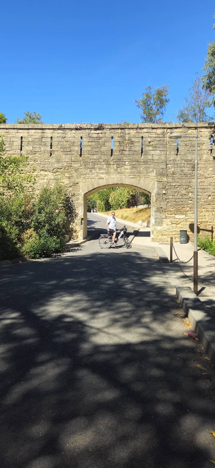 Nicholas cycling beside an old stone arch
