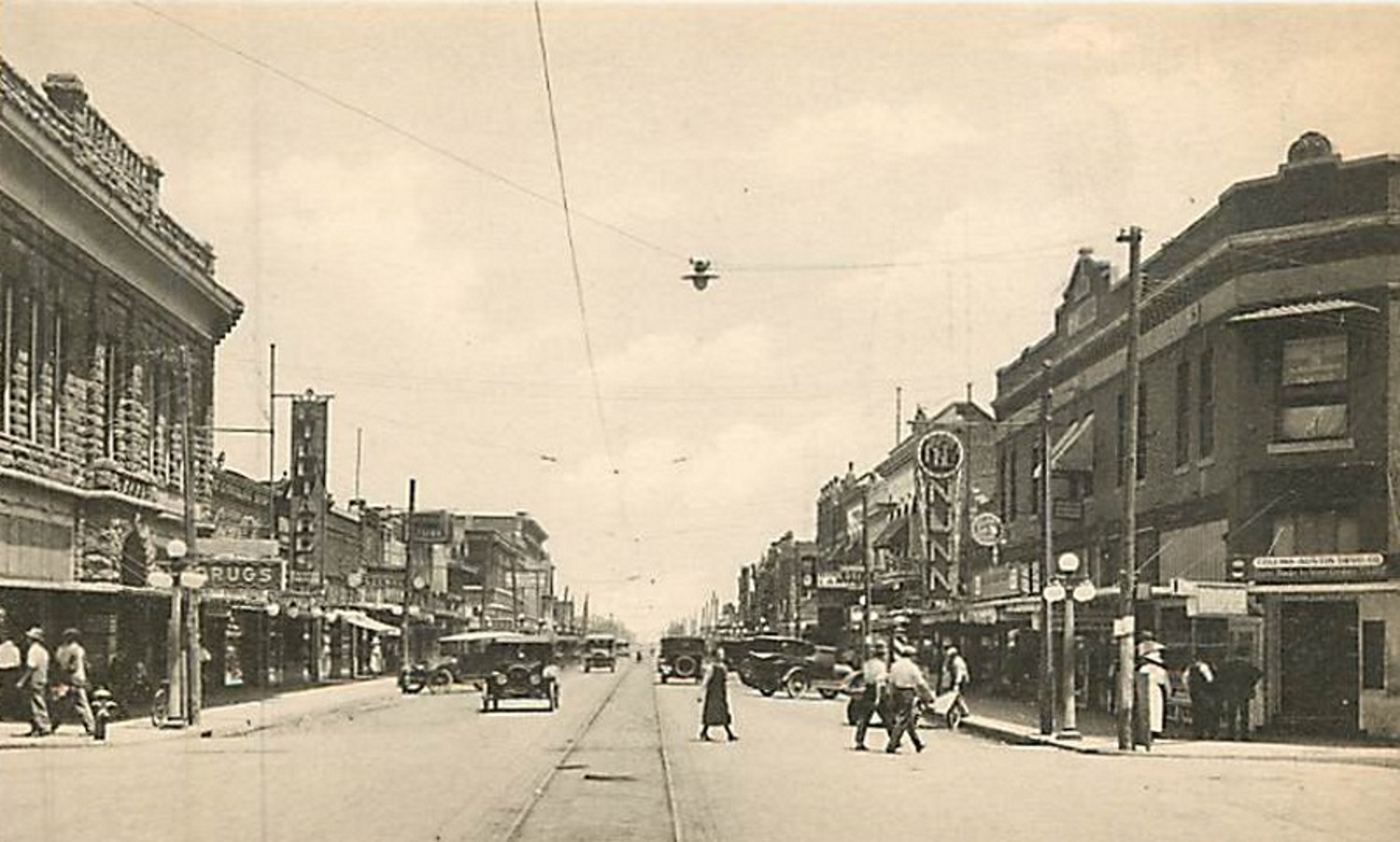 Street Scene showing Dillard's, Drug Store, Nunn's Store, and shoppers dodging Model A's and T's to cross Polk street in Amarillo Texas